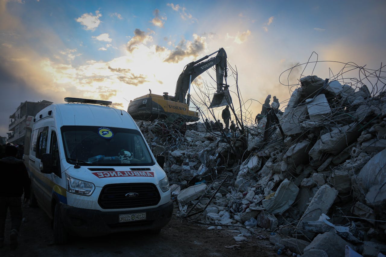 About Emergency responders clear rubble in Idlib, Syria after a natural disaster. Scene highlights urgency and recovery efforts.