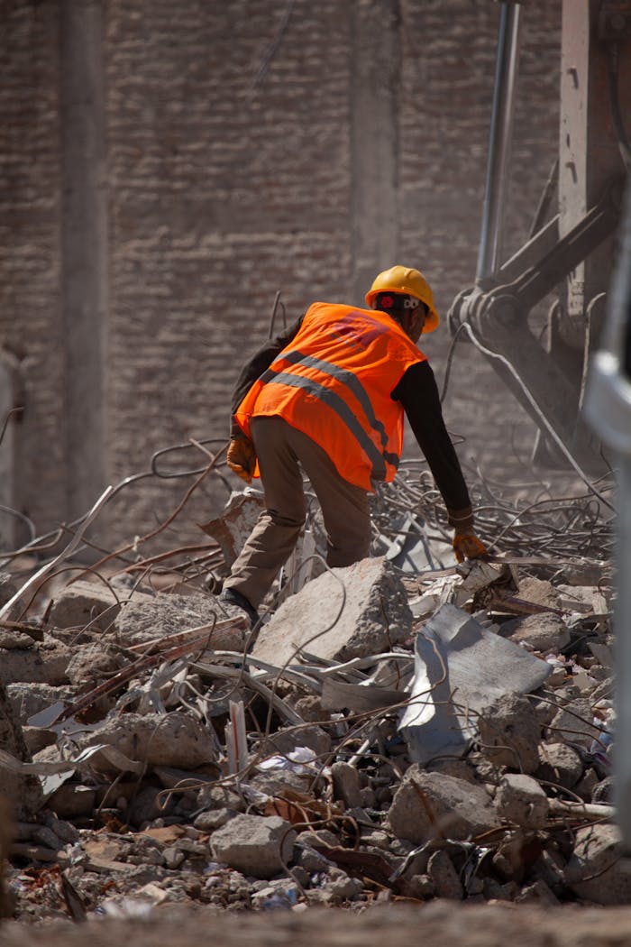 Services Worker wearing a helmet and vest clearing rubble in Malatya, Türkiye.